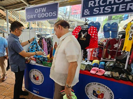 DMW Sec. Cacdac (left) and former Labor Secretary Marianito Roque check on some garments for sale during the launch of the Balik Kabayan Bazaar. (Photo courtesy of CID Communication)