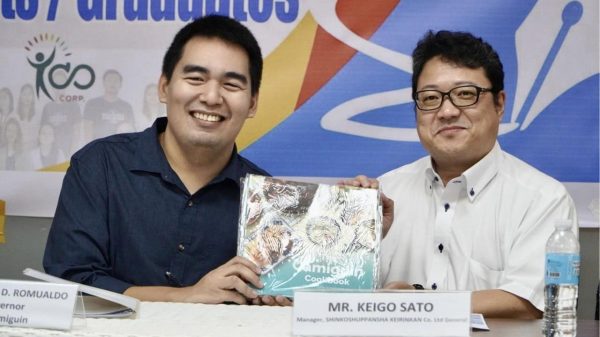 Gov. Xavier Jesus Romualdo (left) shares a Camiguin cookbook with ShinkoShuppansha Keirinkan Co. Manager Keigo Sato (right) during the signing of the partnership agreement. (Photo courtesy of PGO)